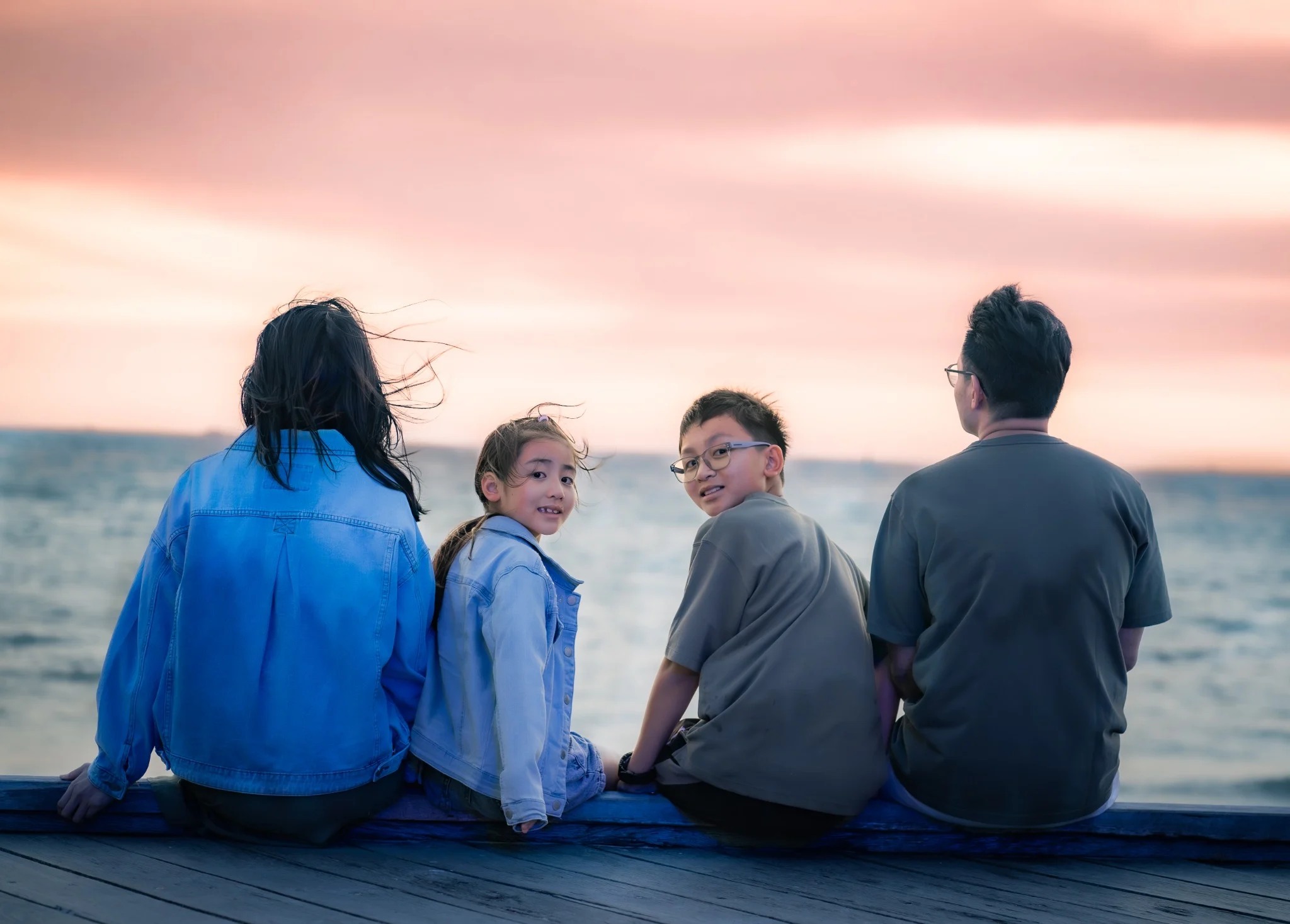 The Chan's Family sitting by the sea at sunset