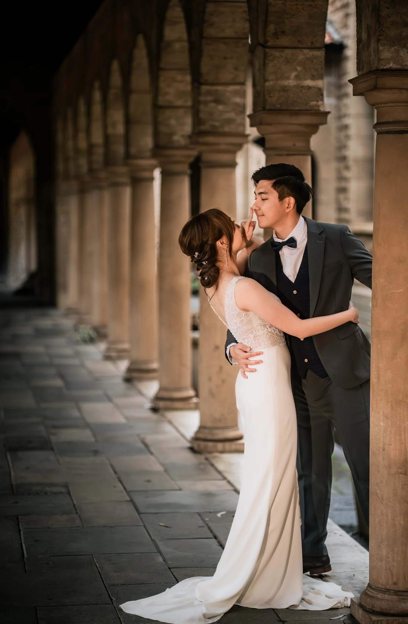 Melody and Ken sharing a playful wedding portrait under UWA arches in Perth, Western Australia