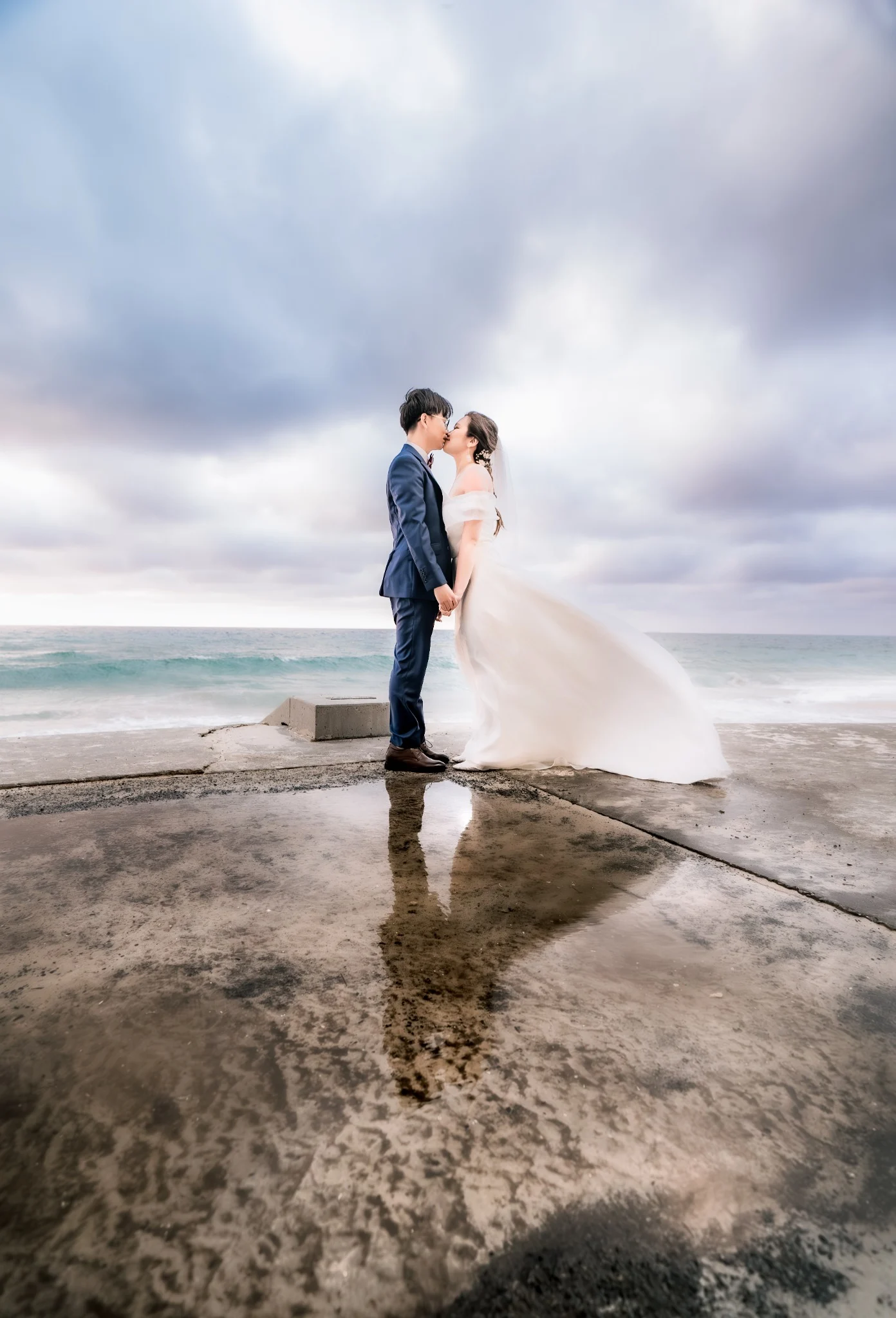 Noel and Brian beside the ocean beneath a dramatic sky