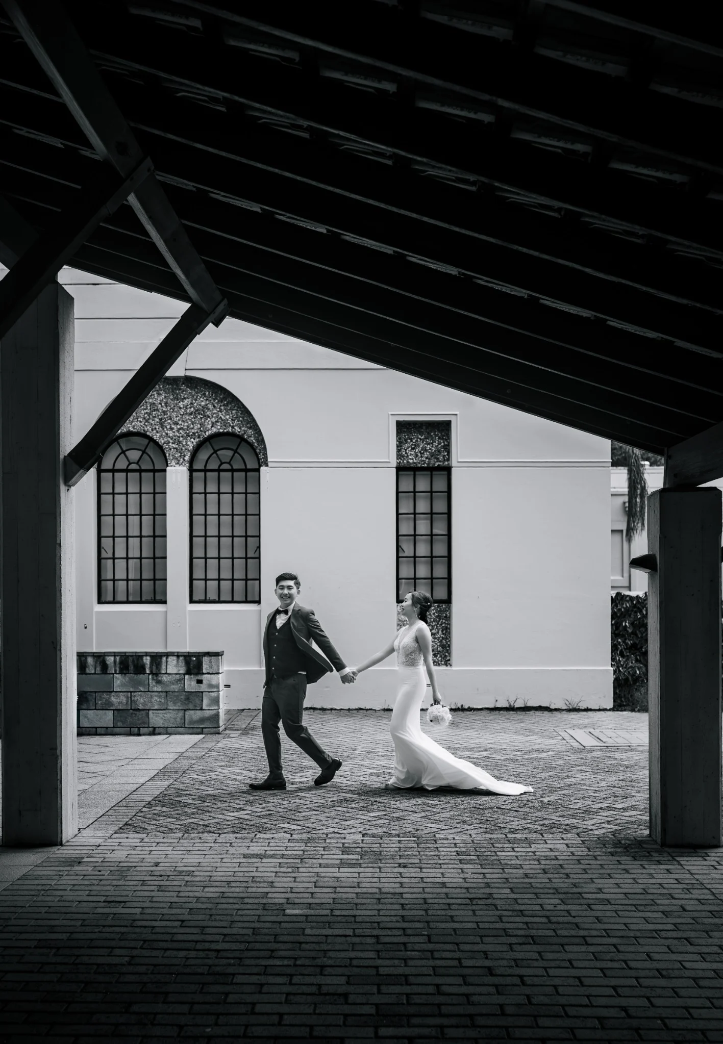 Wedding couple walking through dramatic architectural framing in black and white