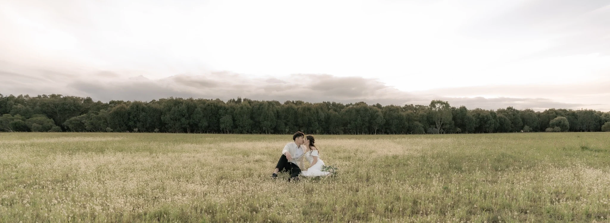Couple seated together in a wide open field during a Perth wedding story session
