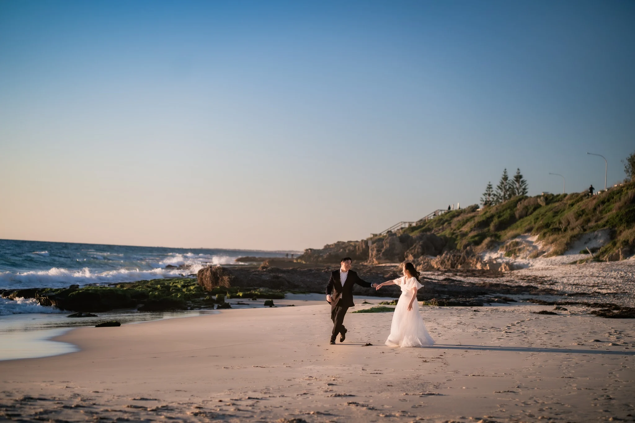 Couple running together at Swanbourne Beach during a Perth pre-wedding session