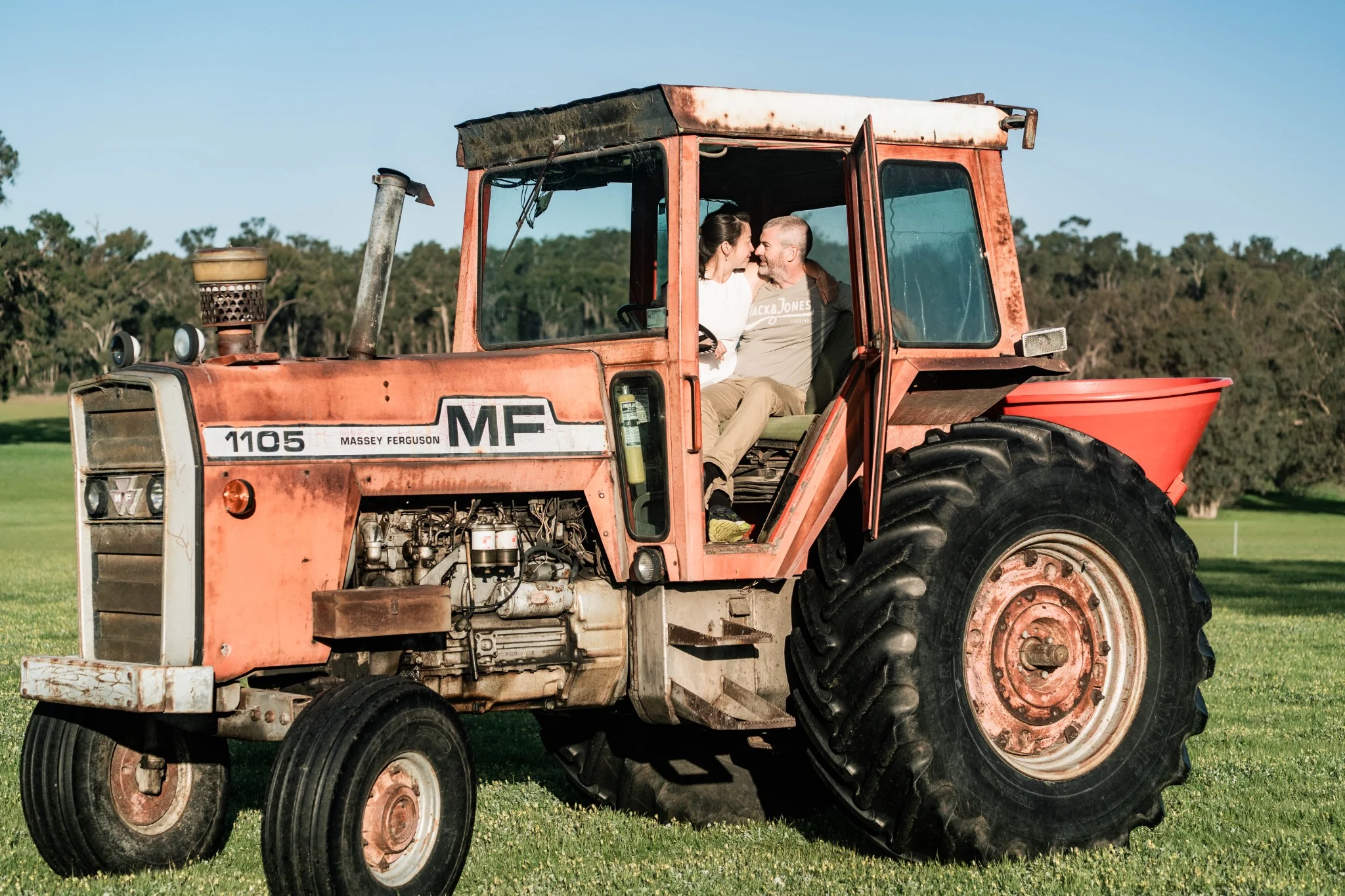 Tammy and her partner sitting on a vintage tractor on a farm near Perth, Western Australia